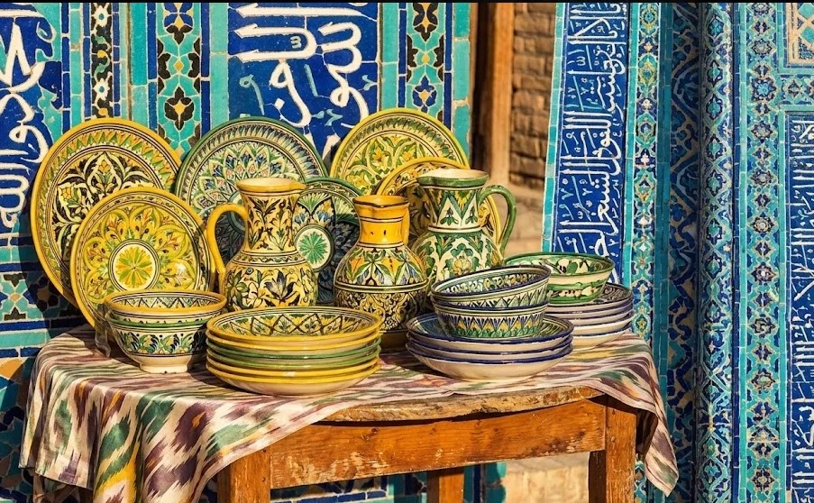 Hand-painted Uzbek ceramic plates and bowls displayed in a traditional artisan workshop, representing Uzbekistan’s art and craft heritage