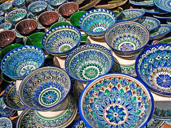 Local Uzbek artisan shaping clay on a pottery wheel in a traditional Gijduvan pottery workshop near Samarkand