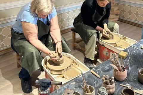 Traditional Gijduvan pottery and hand-painted Uzbek ceramics displayed in a workshop with historic Samarkand tile mosaics