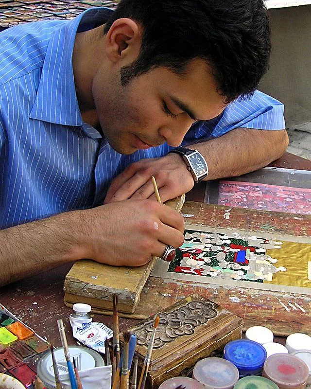 Traditional Uzbek ceramics and miniature paintings displayed in front of the Registan complex in Samarkand, showcasing Silk Road visual arts heritage